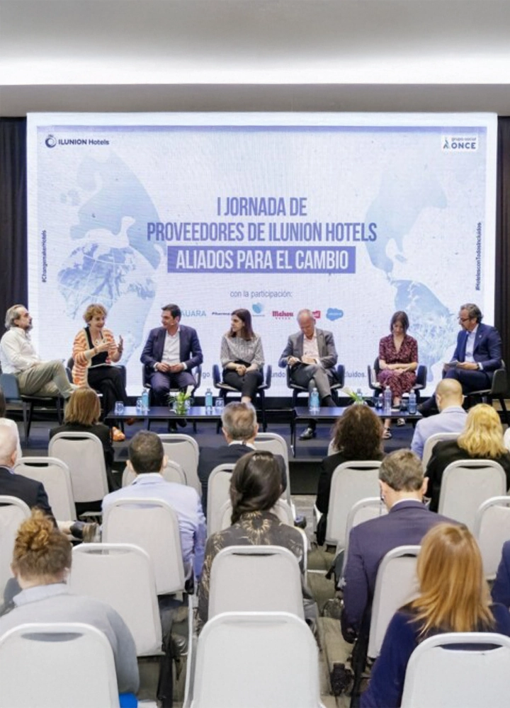 Panel de siete personas sentadas en escenario durante la I Jornada de Proveedores de Ilunion Hotels Aliados para el Cambio, con público frente a ellos