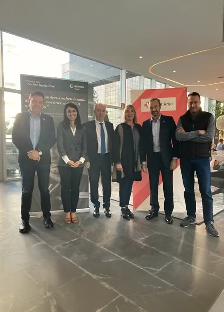 Seis personas posan en un espacio moderno junto a pancartas de ILUNION Hotels y Cruz Roja, en un evento profesional.