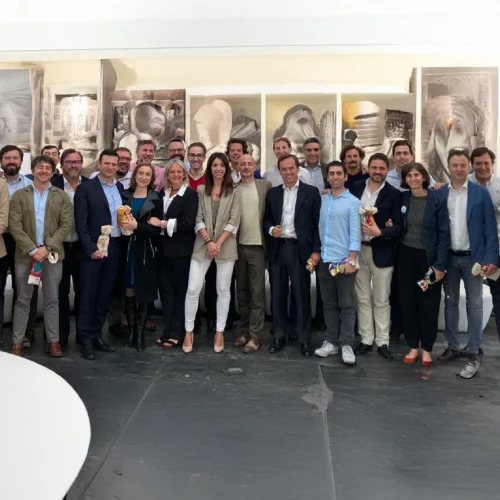 Grupo de personas con ropa formal, posan sonrientes en un espacio interior artístico.