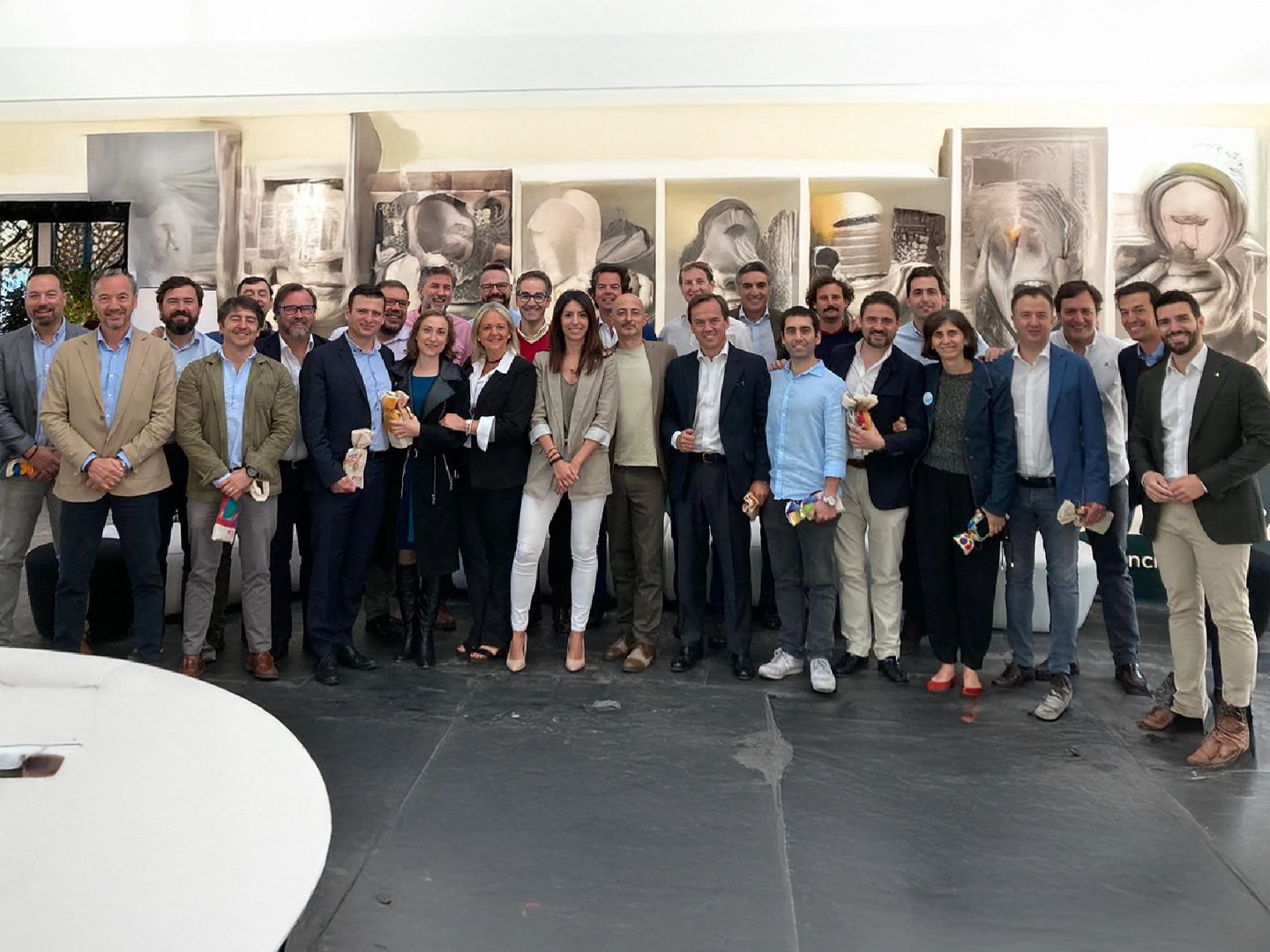 Grupo de personas con ropa formal, posan sonrientes en un espacio interior artístico.