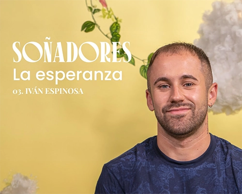 La imagen presenta a un hombre de cabello corto y oscuro, sonriendo ampliamente. Lleva puesto una camiseta azul oscura. De fondo, hay un tono amarillo suave junto con una nubes que transmiten calidez.