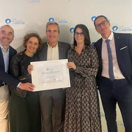 Cinco personas sonríen mientras posan juntas y sostienen un diploma que dice: “Club Excelencia en Gestión, Premio de Buenas Prácticas en Gestión, ILUNION HOTELS”.