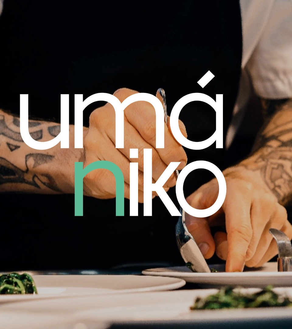 Primer plano de manos tatuadas de un chef emplatando comida con precisión. El texto 'umániko' aparece en tipografía moderna, con las letras 'nik' en color verde, destacando el nombre del restaurante o marca.
