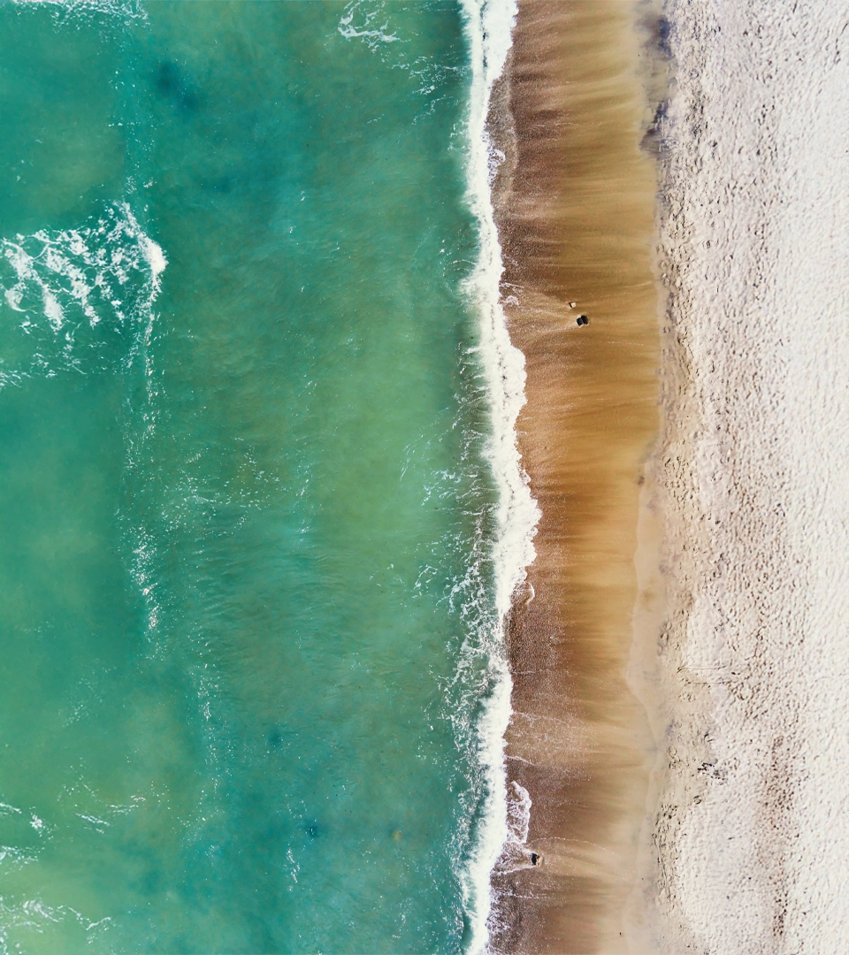Vista aérea de una playa con olas rompiendo en la orilla.