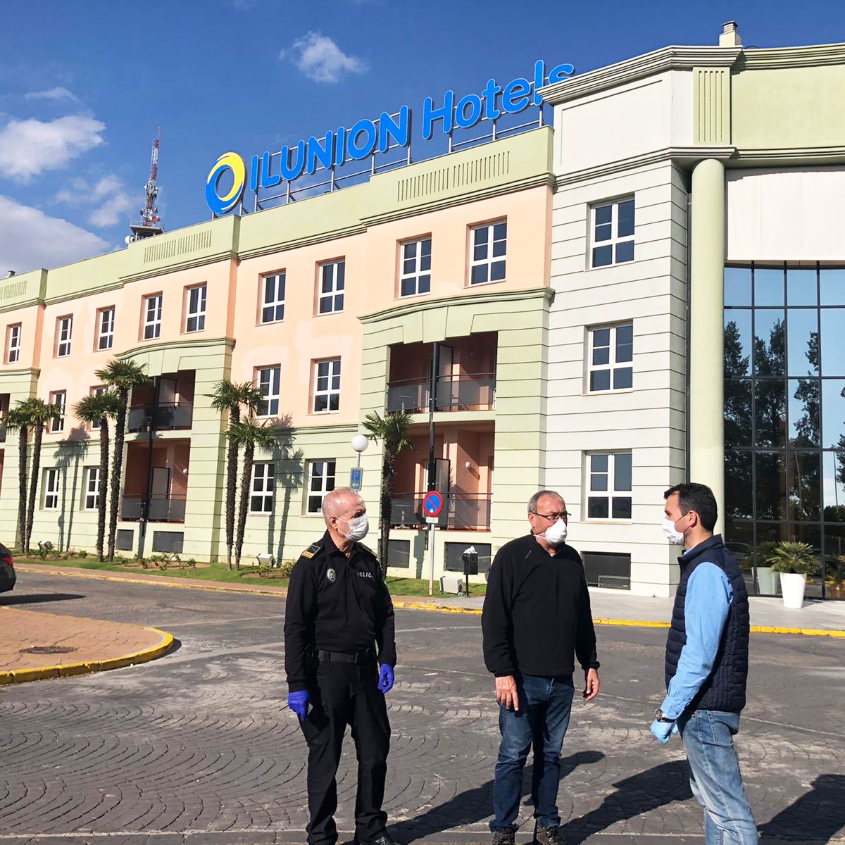 Tres personas de pie delante de la fachada verde de uno de los hoteles de ILUNION Hotels.