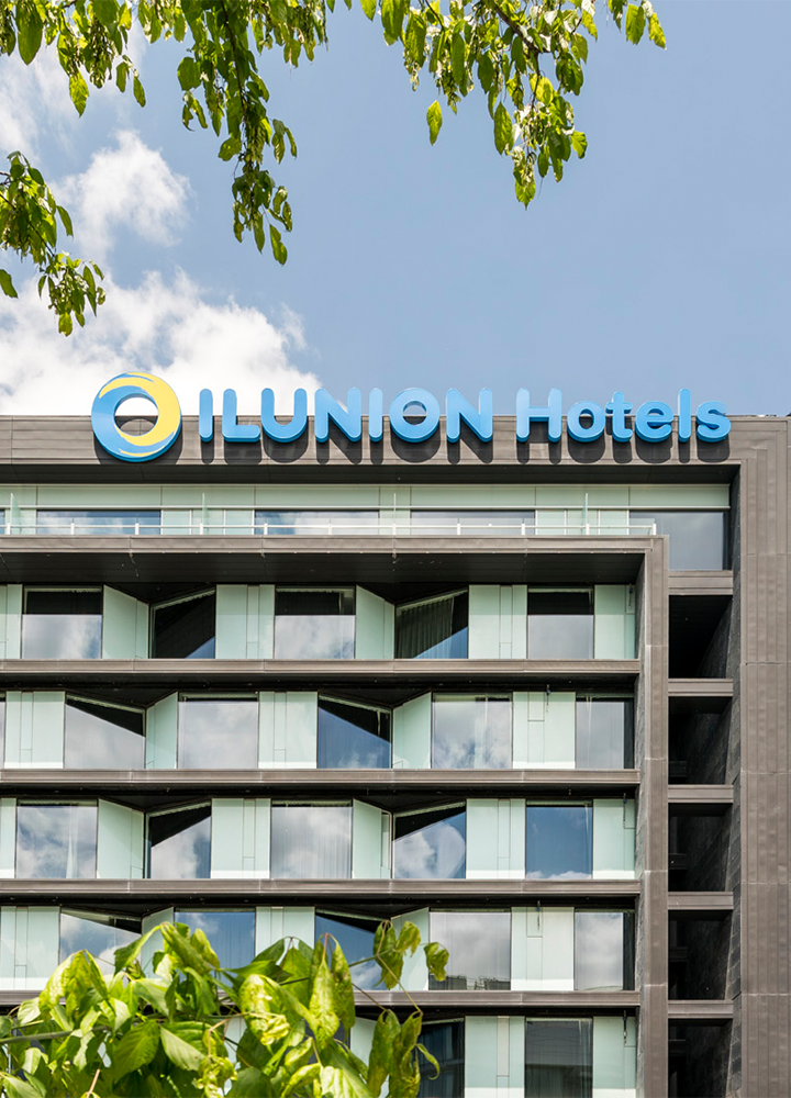 Hotel con fachada de vidrio y el cartel “ILUNION Hotels” en lo alto.