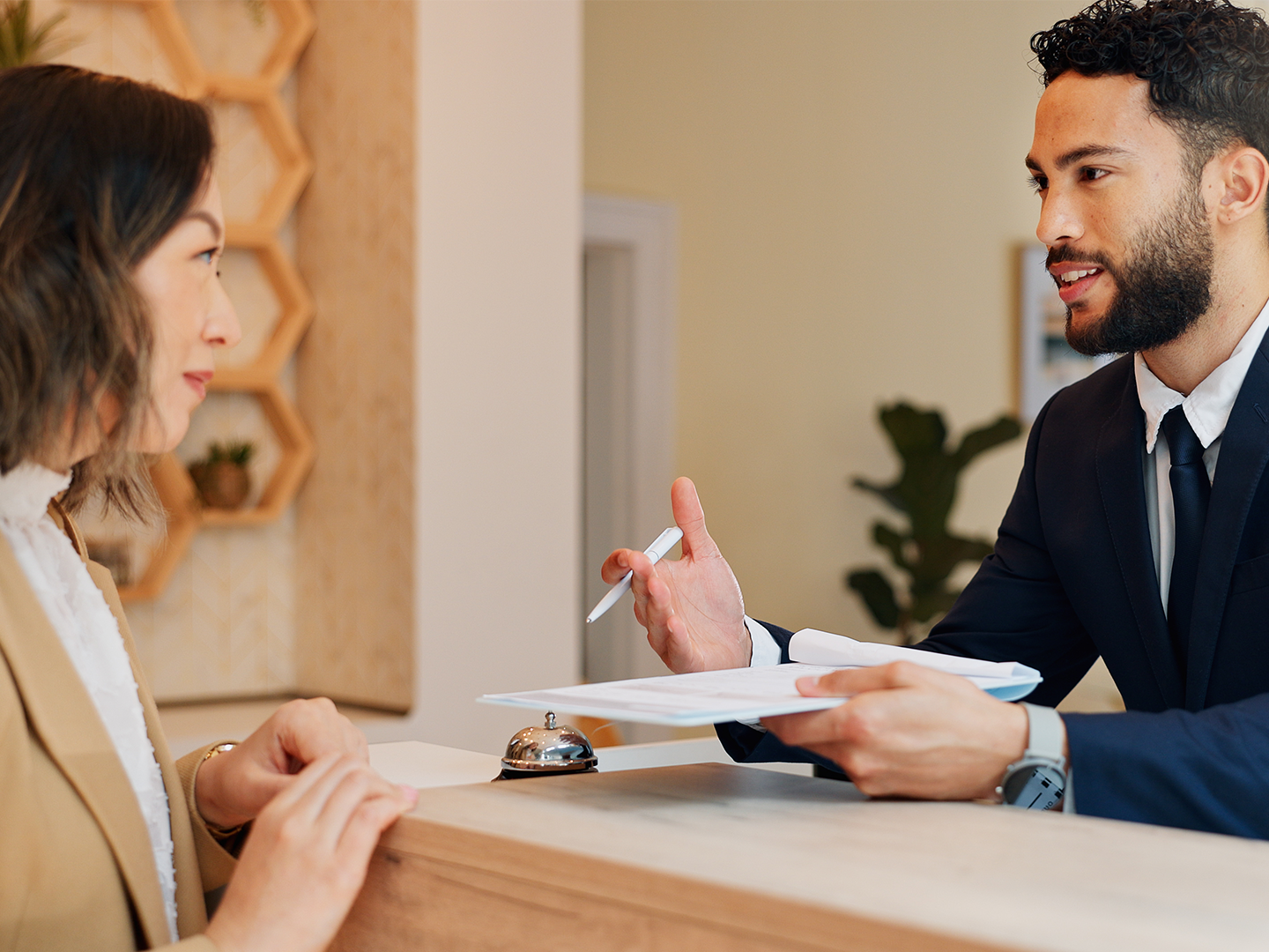 Dos personas hablando en un mostrador de una recepción de hotel.