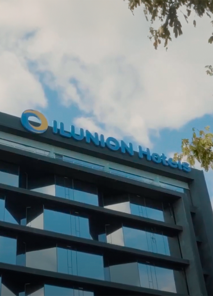 Hotel con fachada de vidrio y el cartel “ILUNION Hotels” en lo alto.
