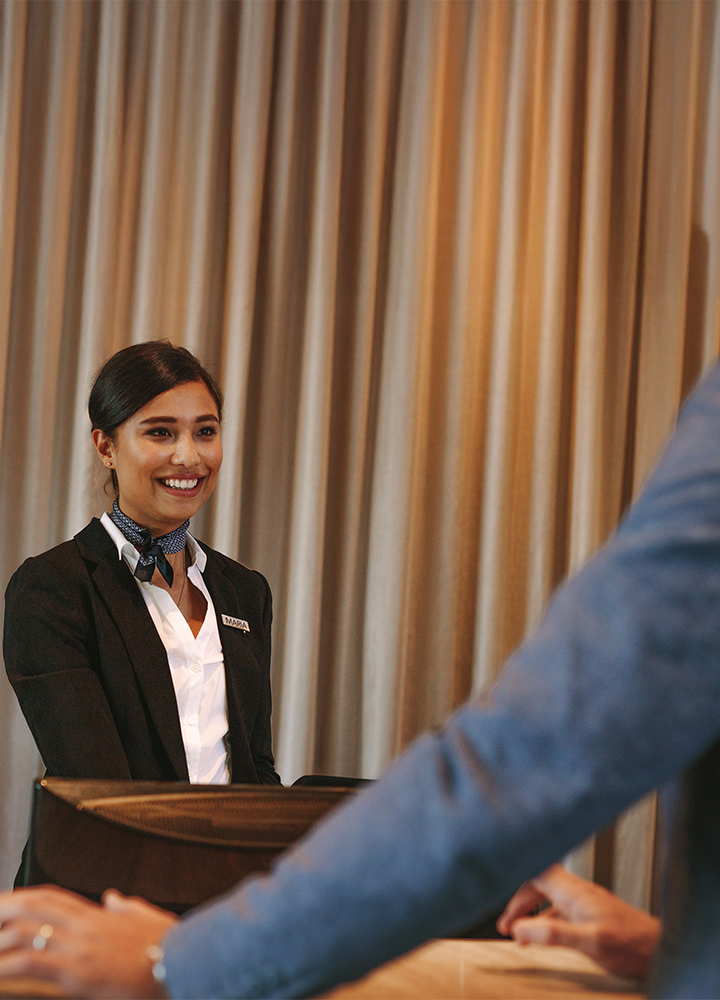 Recepcionista detrás de un mostrador hablando con una persona.