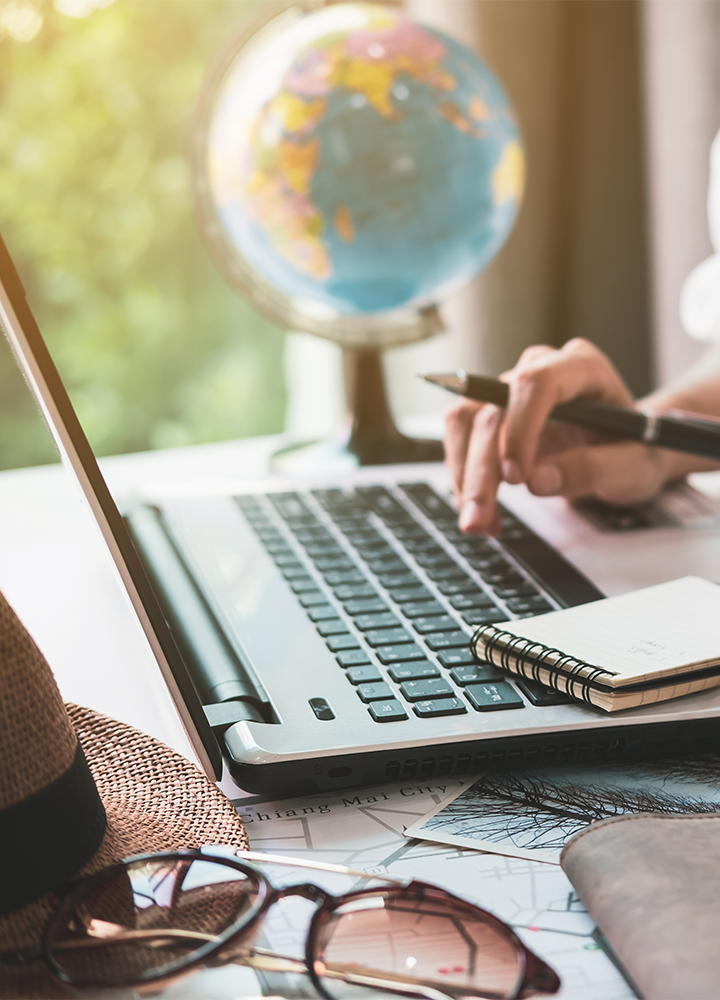Persona con un portátil y una libreta en una mesa.