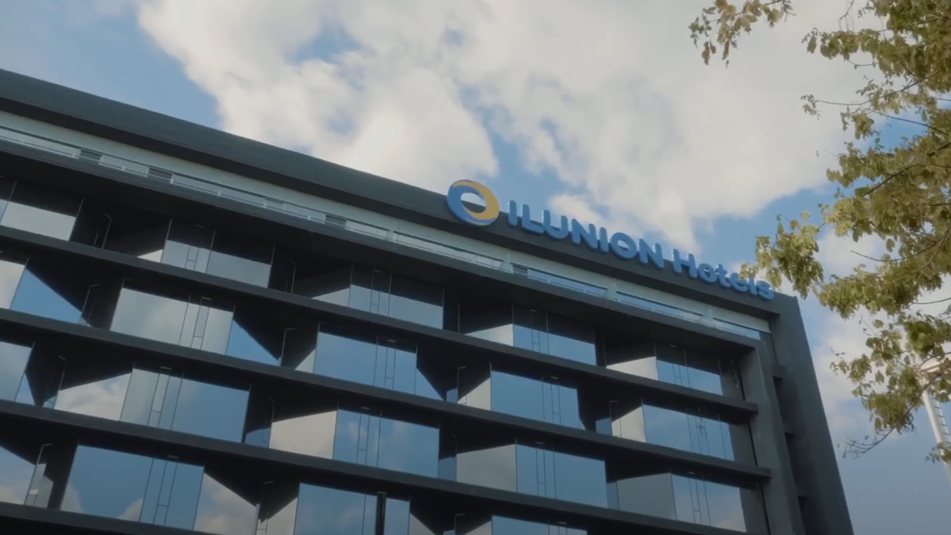 Hotel con fachada de vidrio y el cartel “ILUNION Hotels” en lo alto.