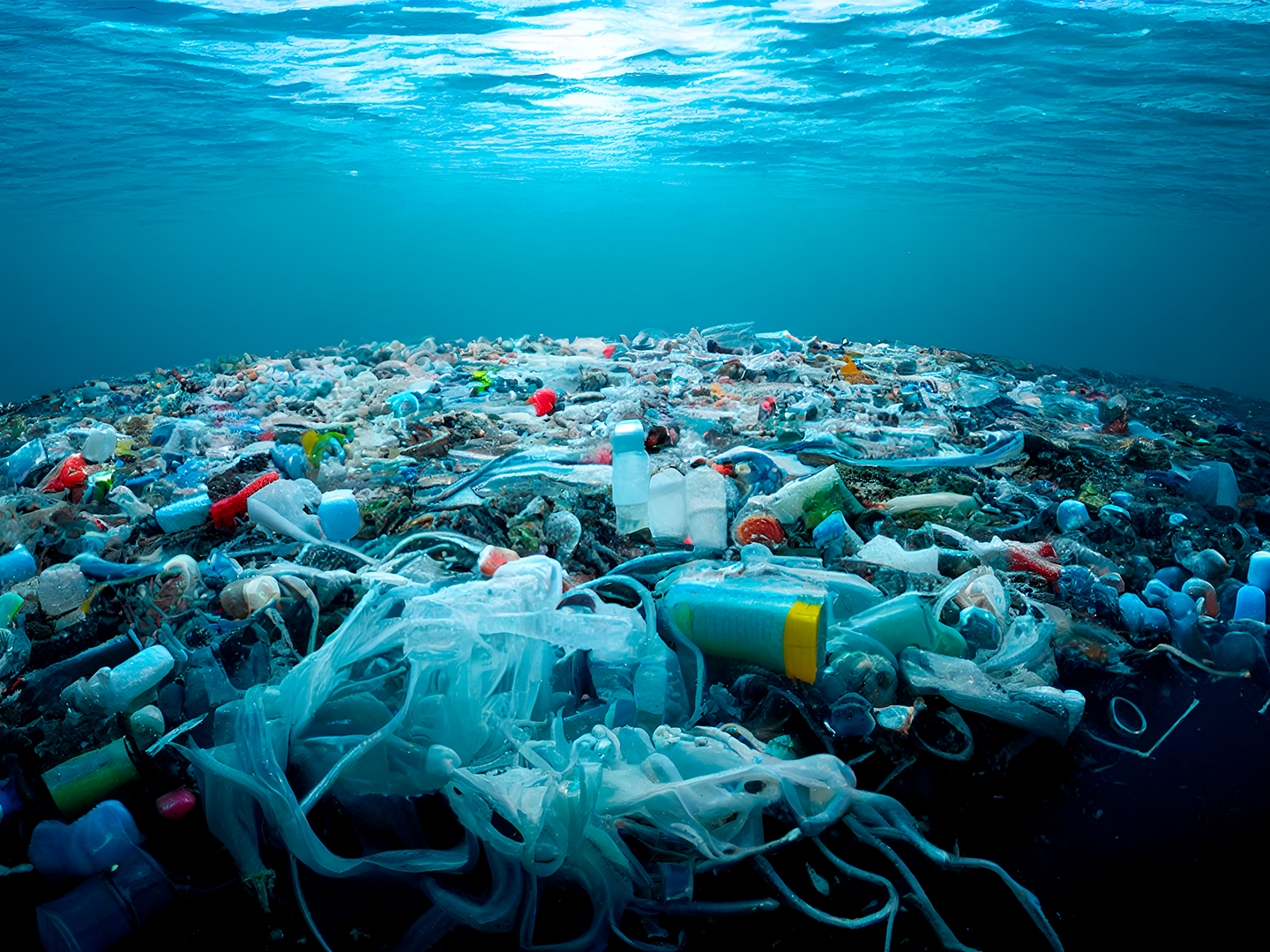 Masa caótica de basura flotante cubre el mar: botellas, bolsas y envases plásticos se mezclan con el agua, mostrando una grave contaminación.