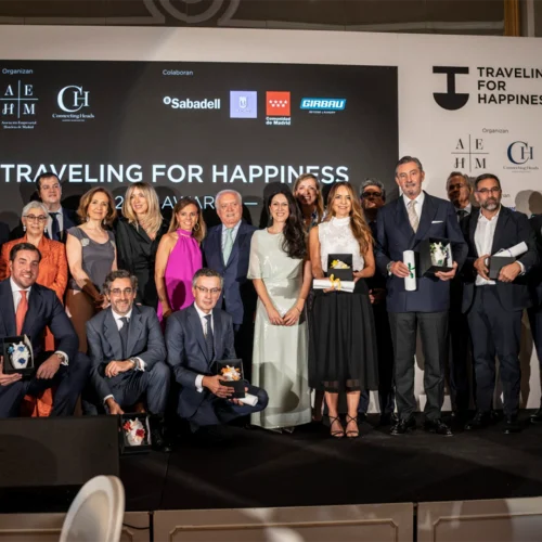 A group of elegantly dressed people stands on stage during an awards ceremony called 