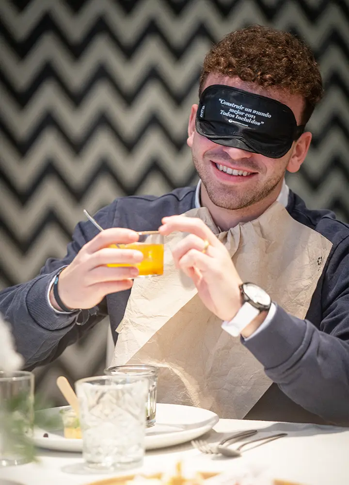 Young man having breakfast wearing an ILUNION Hotels blindfold