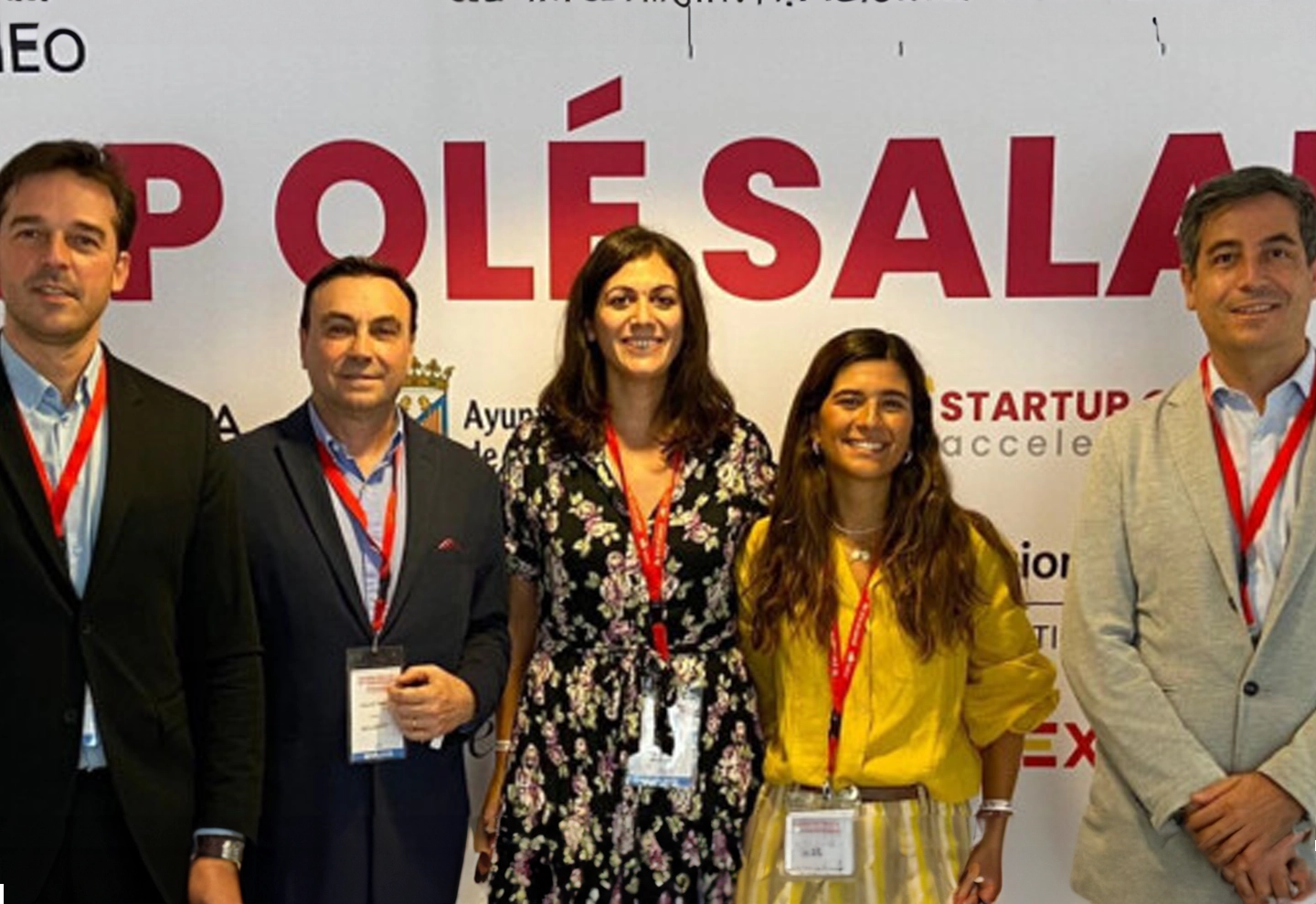 Five people pose together in front of a large white sign with red letters that read “STARTUP OLÉ SALAMANCA.”