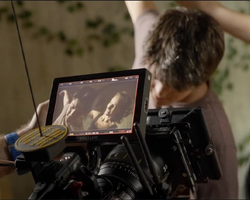 Vista del monitor de una cámara cinematográfica profesional, que muestra una escena de una película mientras el camarógrafo la observa.