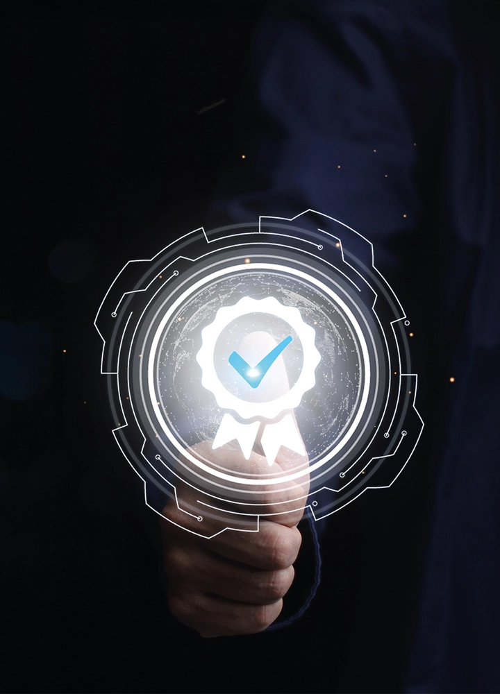 Mano haciendo gesto de aprobación con pulgar arriba sobre fondo oscuro; interfaz digital muestra ícono de calidad y verificación tecnológica.