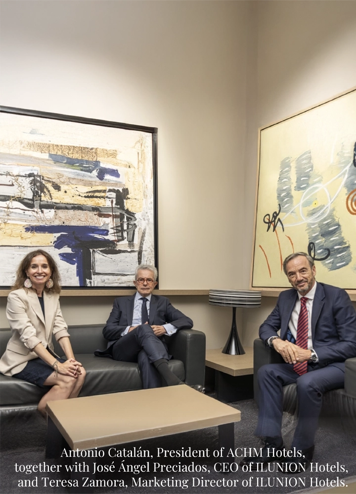 Antonio Catalán, José Ángel Preciados and Teresa Zamora seated in a modern lounge with abstract paintings during a professional meeting.