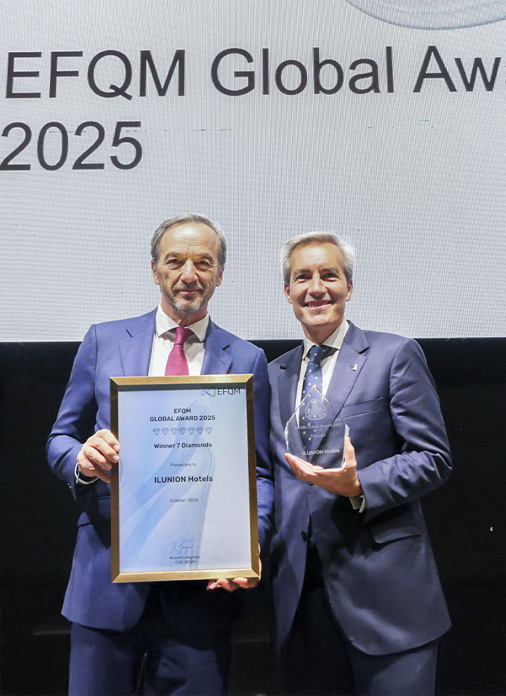 José Ángel Preciados y Alejandro Oñoro en el escenario sosteniendo un diploma y un trofeo del EFQM Global Award 2025 otorgado a ILUNION Hotels