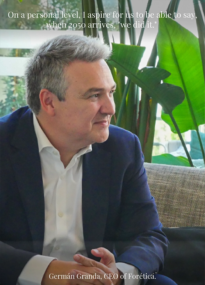 A man seated on a sofa in a modern indoor setting with large green plants in the background, wearing a dark suit and white shirt. Upper text reads: ‘On a personal level, I aspire for us to be able to say, when 2050 arrives, “we did it.”’ Lower text reads: ‘Germán Granda, CEO of Forética.’
