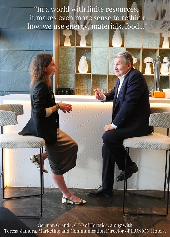 A man and a woman seated on bar stools in a modern setting with a decorative shelf and warm lighting. Upper text reads: ‘In a world with finite resources, it makes even more sense to rethink how we use energy, materials, food...’ Lower text reads: ‘Germán Granda, CEO of Forética, along with Teresa Zamora, Marketing and Communication Director of ILUNION Hotels.’
