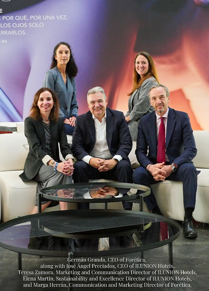 Five people in business attire posing in a modern indoor setting with sofas and glass tables, against a backdrop featuring promotional text. Lower text reads: Germán Granda, CEO of Forética, along with José Ángel Preciados, CEO of ILUNION Hotels; Teresa Zamora, Marketing and Communication Director of ILUNION Hotels; Elena Martín, Sustainability and Excellence Director of ILUNION Hotels; and Marga Herrán, Communication and Marketing Director of Forética.
