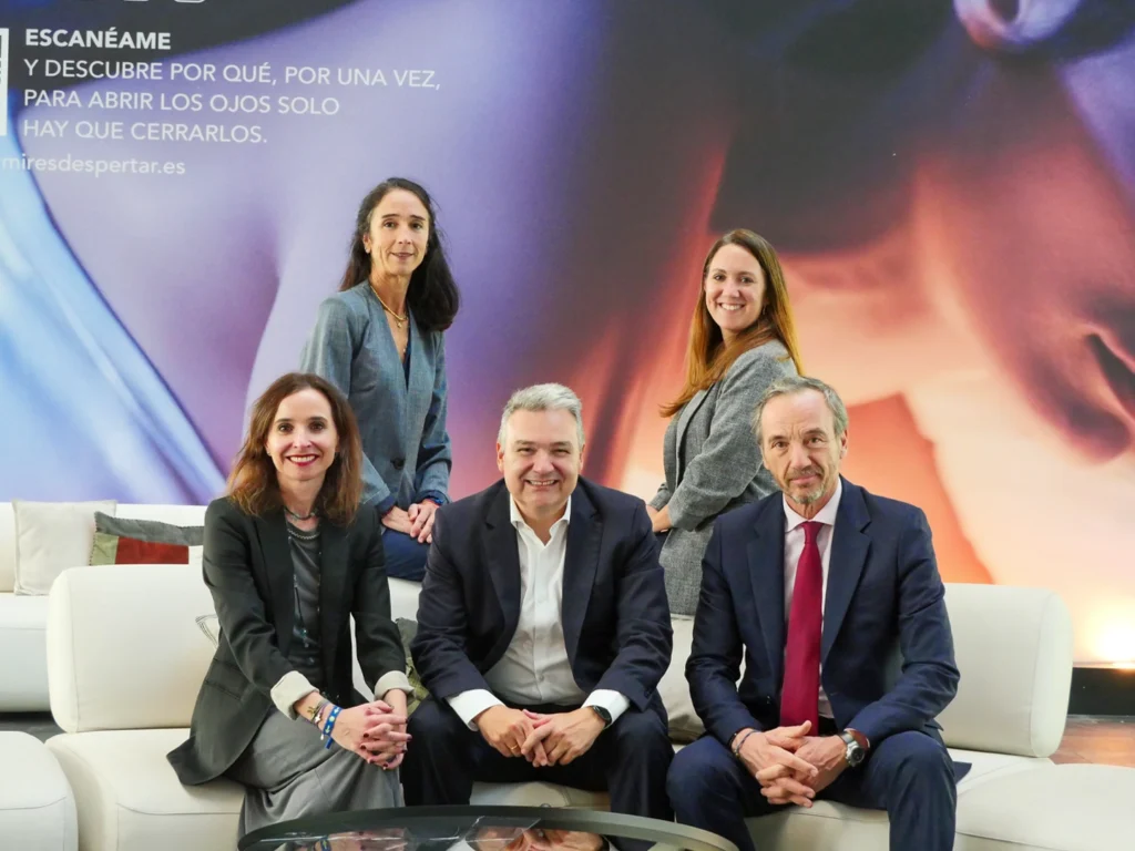 Cinco ejecutivos, tres mujeres y dos hombres, sentados en un sofá blanco. Fondo con el texto 
