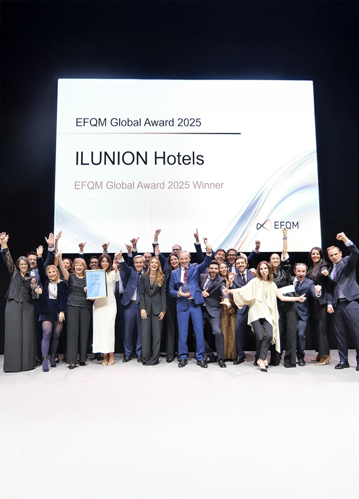 Grupo de personas celebrando en escenario con pantalla que anuncia EFQM Global Award 2025 para ILUNION Hotels.
