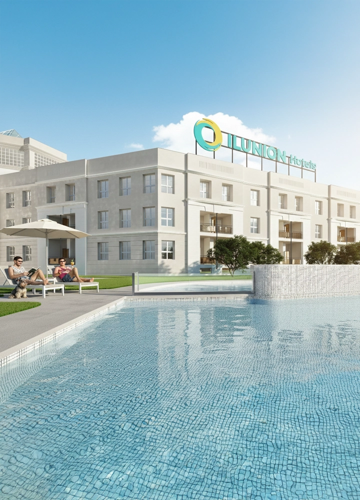 Piscina exterior frente a un edificio moderno con el logotipo de ILUNION Hotels; dos personas descansan en tumbonas bajo una sombrilla en zona ajardinada.