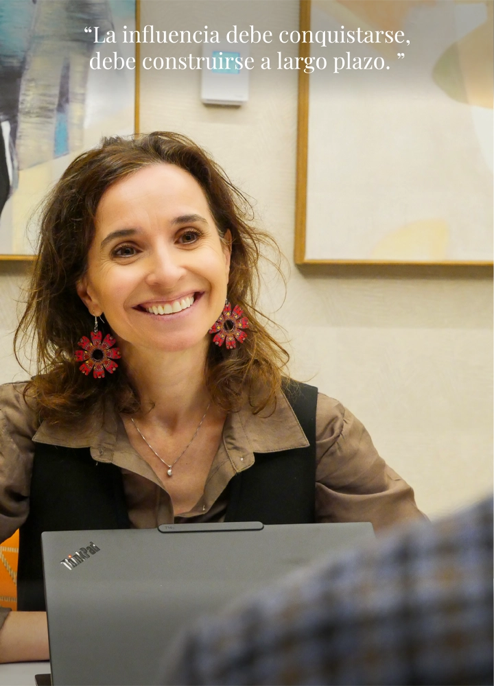 Mujer sentada frente a un portátil en una mesa; en la parte superior se lee la frase: 'La influencia debe conquistarse, debe construirse a largo plazo.