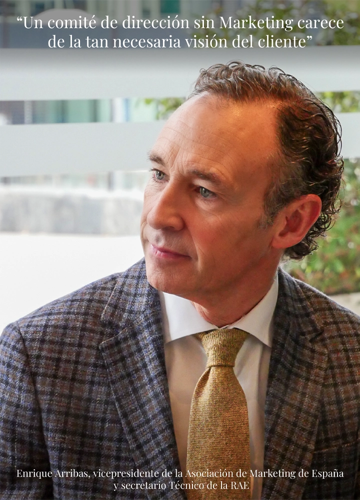 Hombre con chaqueta de cuadros y corbata dorada sentada frente a fondo claro; se lee la frase: 'Un comité de dirección sin Marketing carece de la visión del cliente.