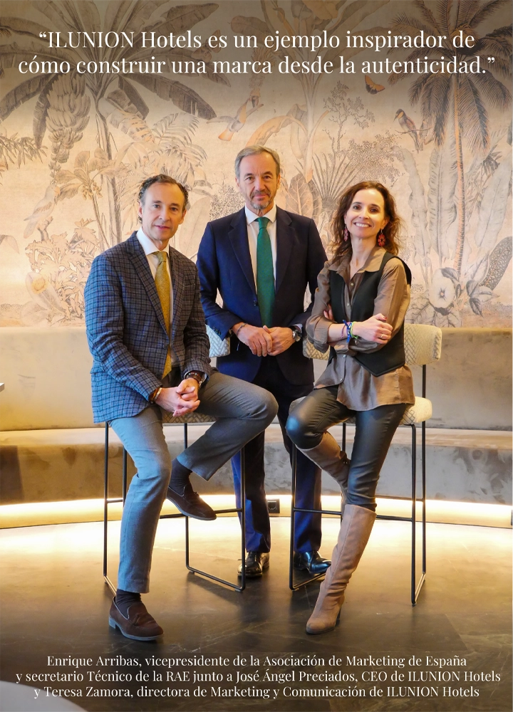 Dos hombres y una mujer posando en un espacio interior elegante con mural decorativo y la frase: ILUNION Hotels es un ejemplo inspirador de cómo construir una marca desde la autenticidad.