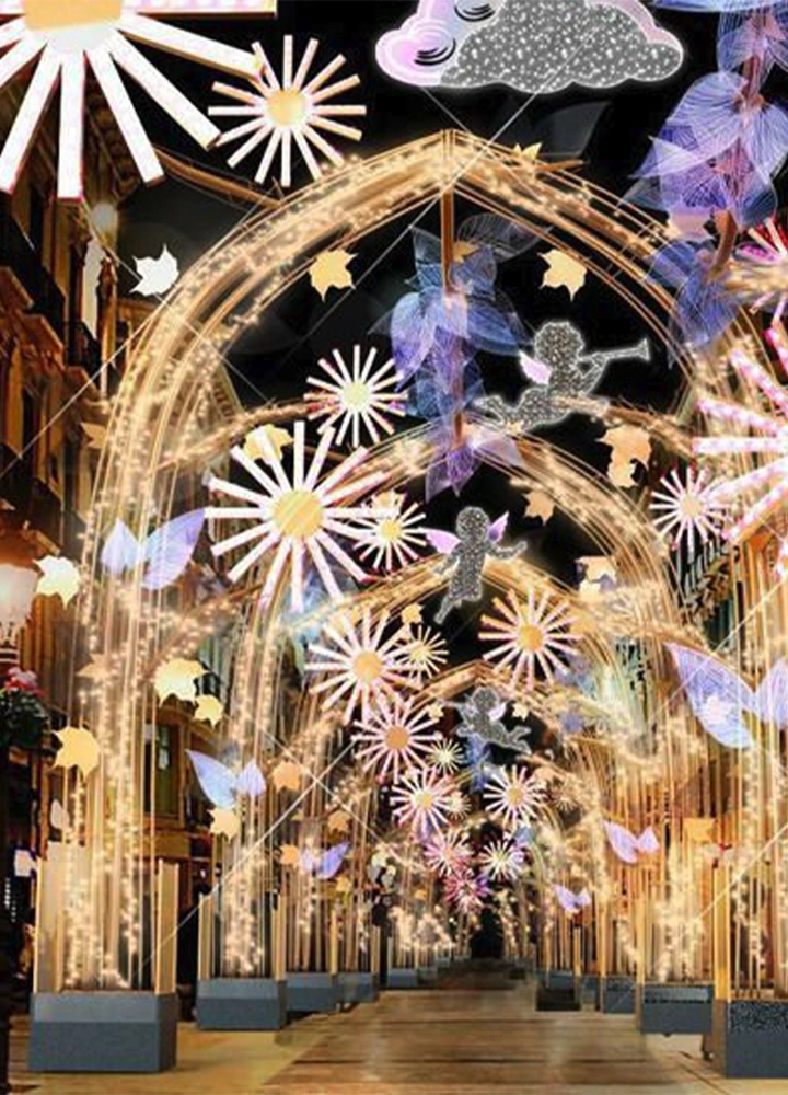Calle decorada con arcos iluminados y figuras navideñas como soles, nubes y ángeles, creando un túnel de luces festivas