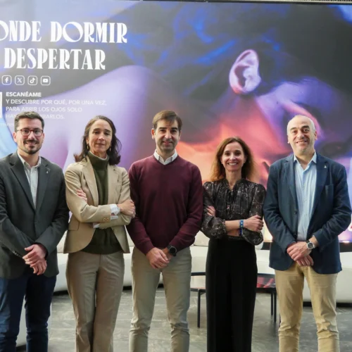 Cinco personas posando frente a un gran cartel promocional con el mensaje “Donde dormir es despertar” en un espacio interior moderno
