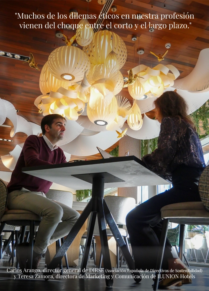 Un hombre y una mujer conversan sentados frente a frente en una mesa de un restaurante moderno, bajo una decoración de lámparas colgantes de diseño. En la parte superior de la imagen pone: 