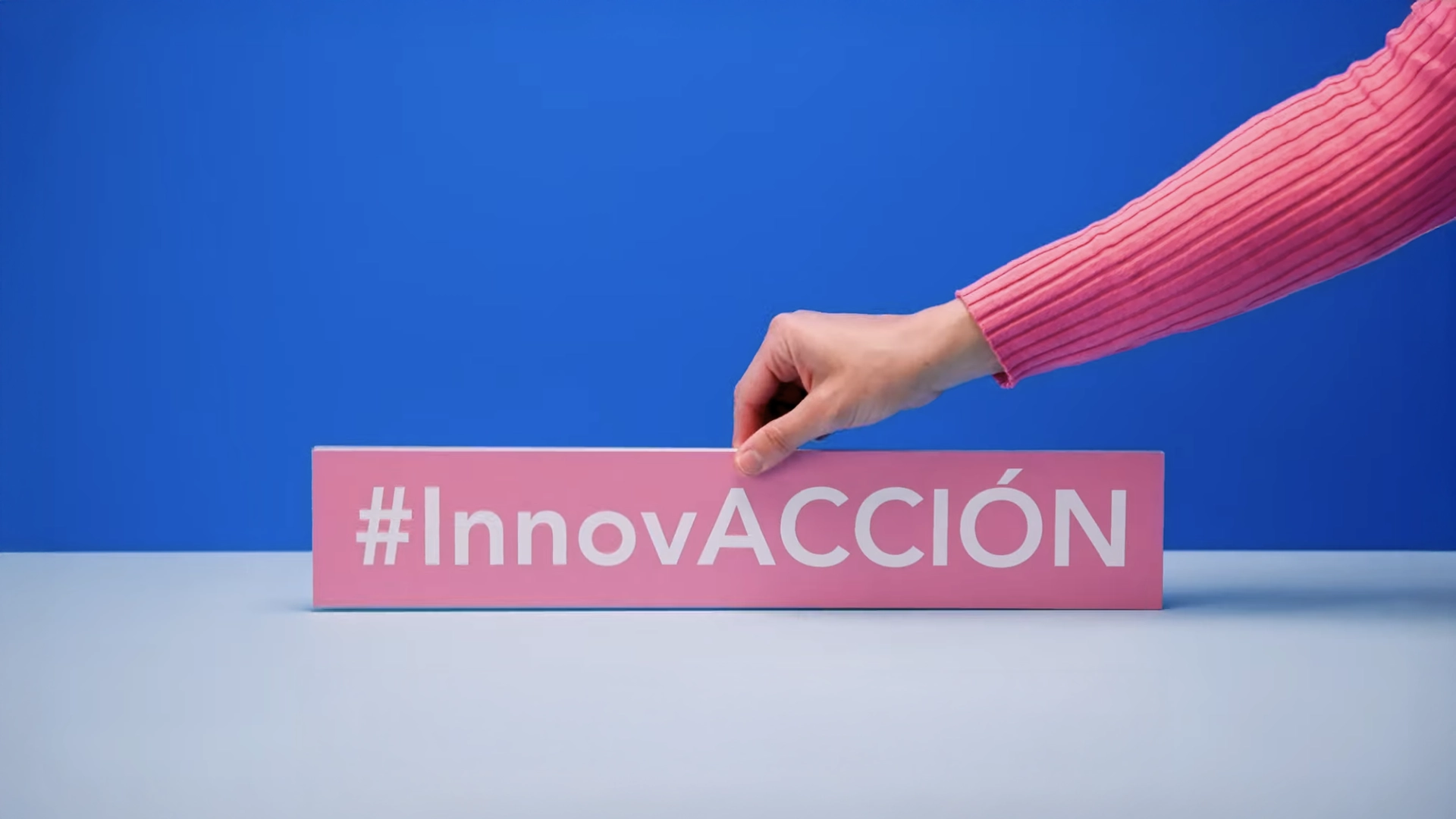 Mano sujetando un cartel rosa con el hashtag blanco 