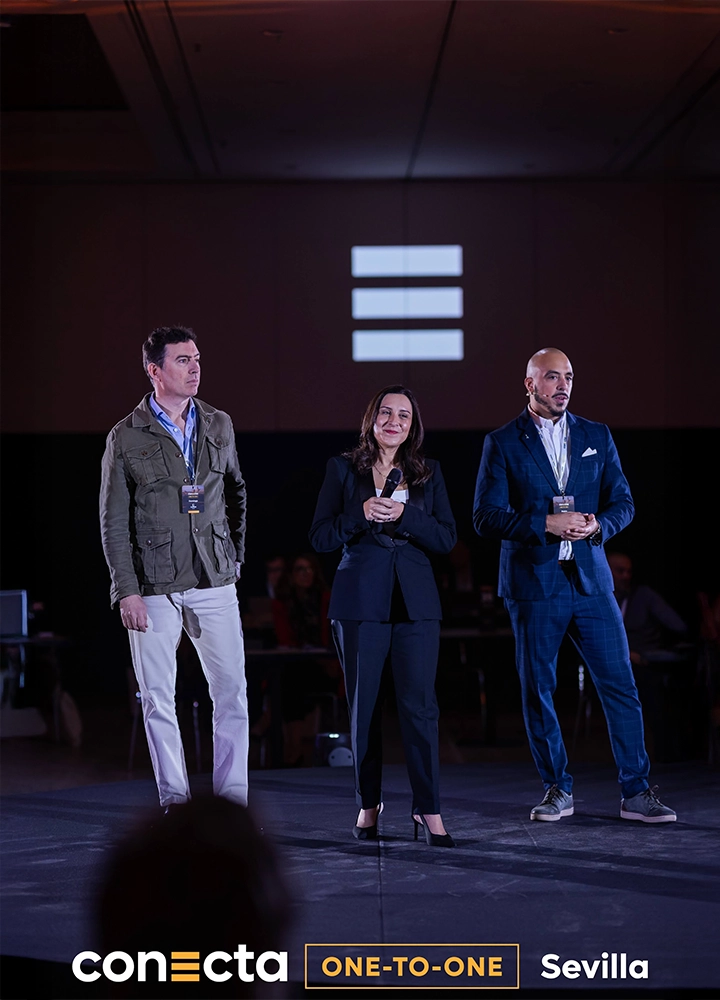 Tres ponentes sobre un escenario oscuro durante el evento 