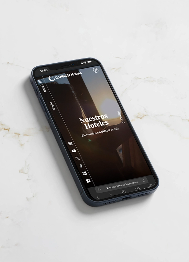 Un smartphone situado sobre una superficie de mármol blanco mostrando la página web de ILUNION Hotels. En la pantalla se lee 