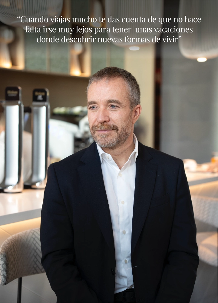 Retrato de perfil de Miguel Sanz, director general de Turespaña, sentado en una barra moderna sosteniendo una taza de café. En la parte superior se lee la cita: 