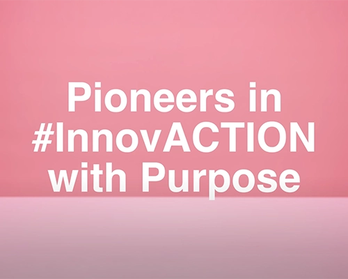 Texto en letras blancas sobre un fondo de color rosa suave que dice: 'Pioneers in #InnovACTION with Purpose'
