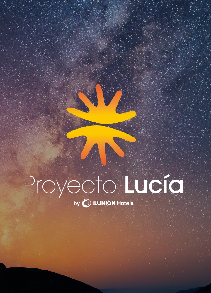 Composición visual con un cielo nocturno estrellado y la Vía Láctea de fondo. En la esquina inferior izquierda, se ve la silueta de una persona sobre una roca señalando hacia el cielo. En el centro, destaca el logotipo del 'Proyecto Lucía' compuesto por un icono solar amarillo y naranja, seguido del texto 'Proyecto Lucía by ILUNION Hotels'. El horizonte muestra siluetas de montañas bajo una luz cálida de atardecer o amanecer.