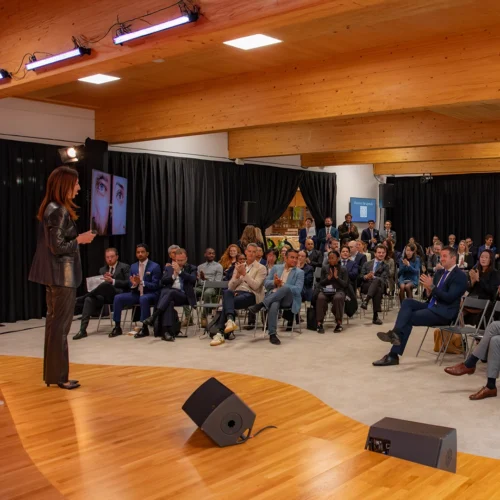 Ponencia en un evento profesional ante un auditorio lleno de asistentes sentados.