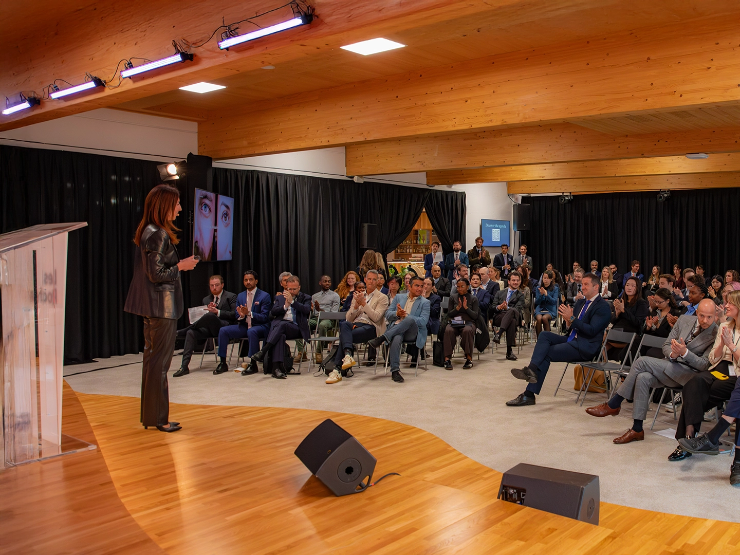Ponencia en un evento profesional ante un auditorio lleno de asistentes sentados.