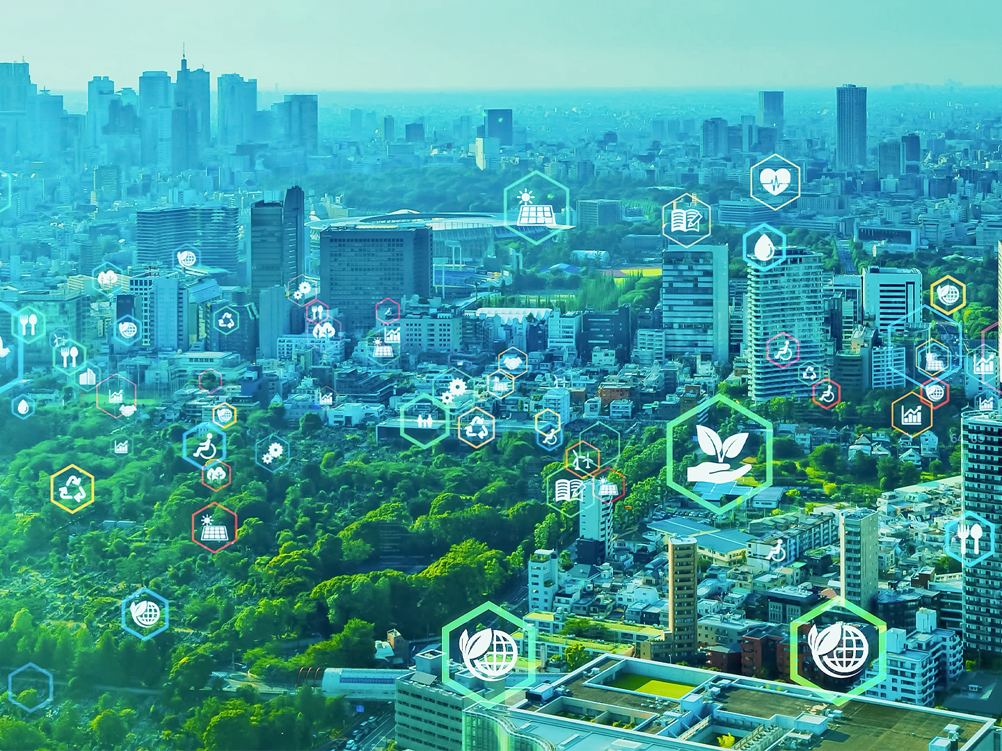 Vista aérea de una gran ciudad con amplias zonas verdes integradas entre edificios y rascacielos. Sobre el paisaje aparecen iconos semitransparentes relacionados con sostenibilidad, reciclaje, energías renovables, salud, educación, movilidad y eficiencia energética. La composición crea una representación visual de una ciudad inteligente y sostenible, combinando naturaleza, desarrollo urbano y tecnología sobre un fondo en tonos verdes y azules.