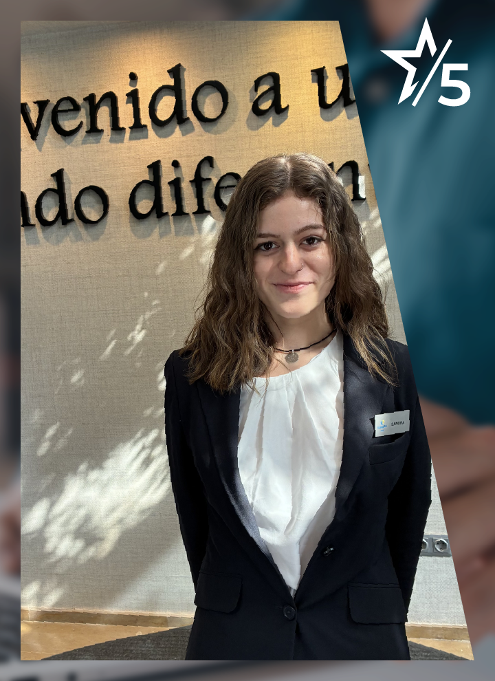 Persona con chaqueta oscura y camisa blanca posando frente a una pared interior con texto decorativo en gran formato parcialmente visible al fondo. En la esquina superior derecha aparece un símbolo de estrella acompañado del número “5”. La composición tiene un diseño corporativo que combina la fotografía principal con elementos gráficos en tonos azulados y fondo desenfocado.