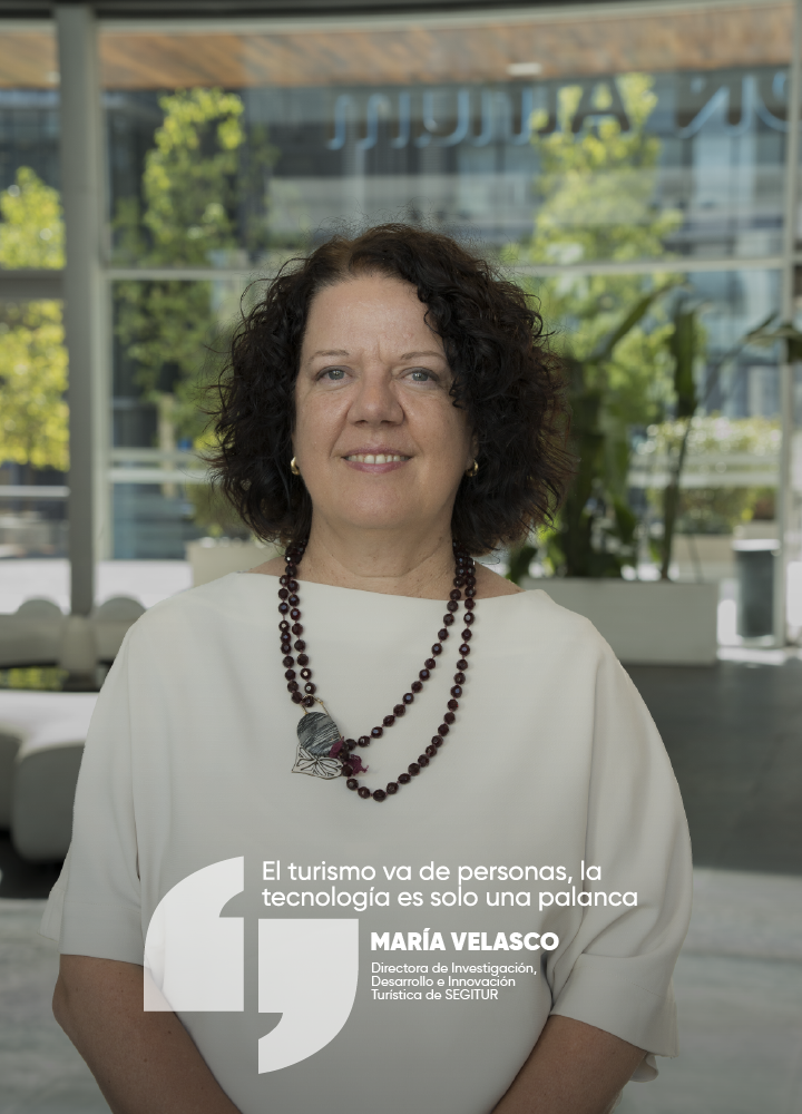 Retrato de una persona posando de frente en un espacio interior luminoso. Viste una blusa clara y un collar de cuentas oscuras. En la parte inferior aparece una cita sobre turismo y tecnología junto a un cargo relacionado con innovación turística.