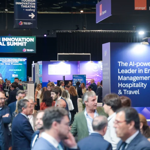 Zona expositiva del Tourism Innovation Global Summit, con numerosos asistentes recorriendo los estands y carteles de empresas tecnológicas del sector turístico.