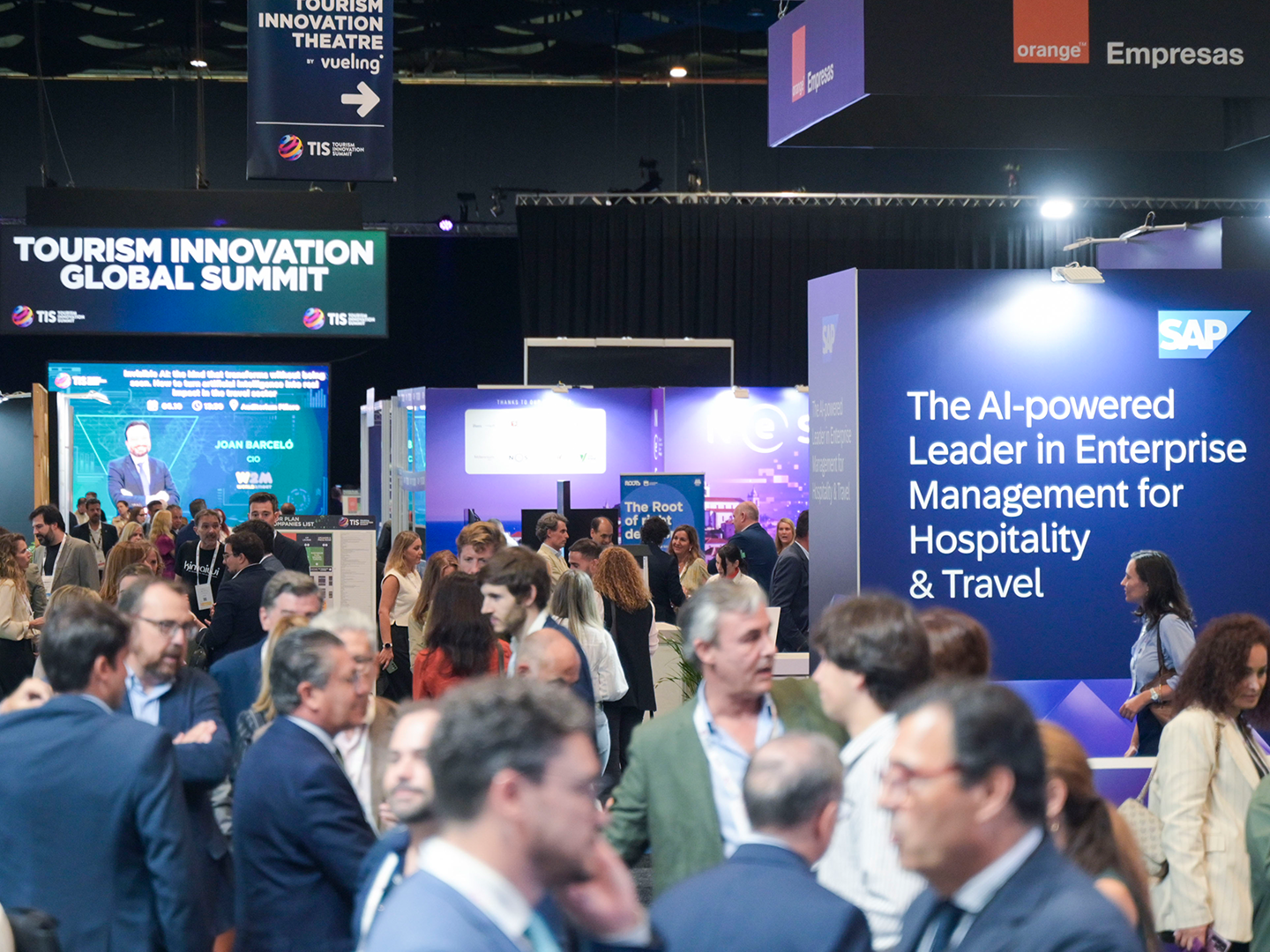 Zona expositiva del Tourism Innovation Global Summit, con numerosos asistentes recorriendo los estands y carteles de empresas tecnológicas del sector turístico.